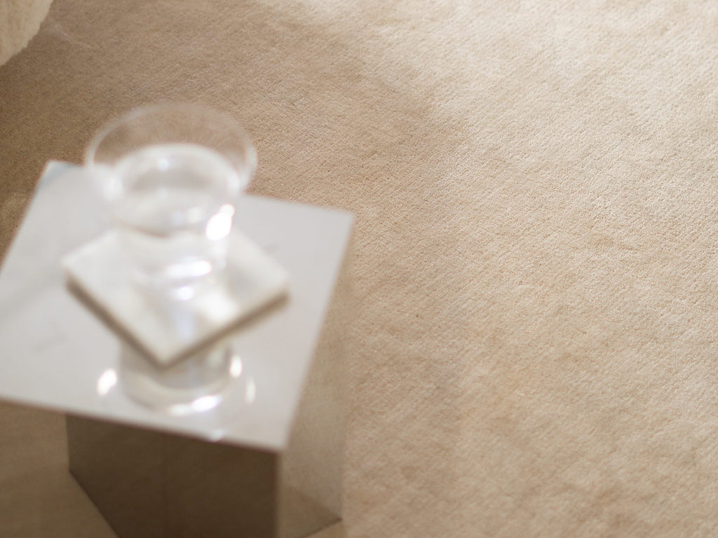 Handcrafted beige rug by Massimo Copenhagen with glass cup on minimalist table