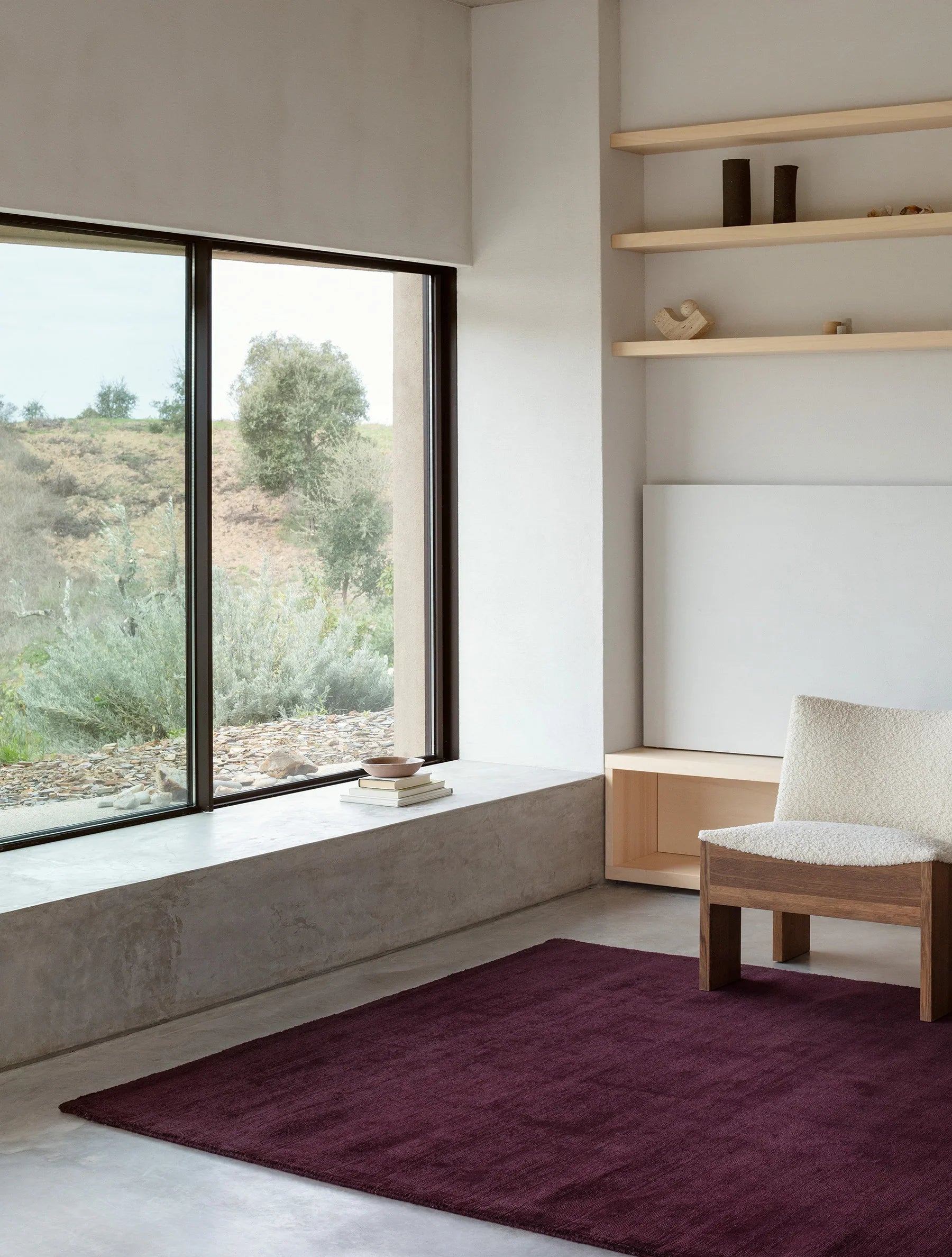 Modern interior with large windows, a purple rug, and minimal furniture.