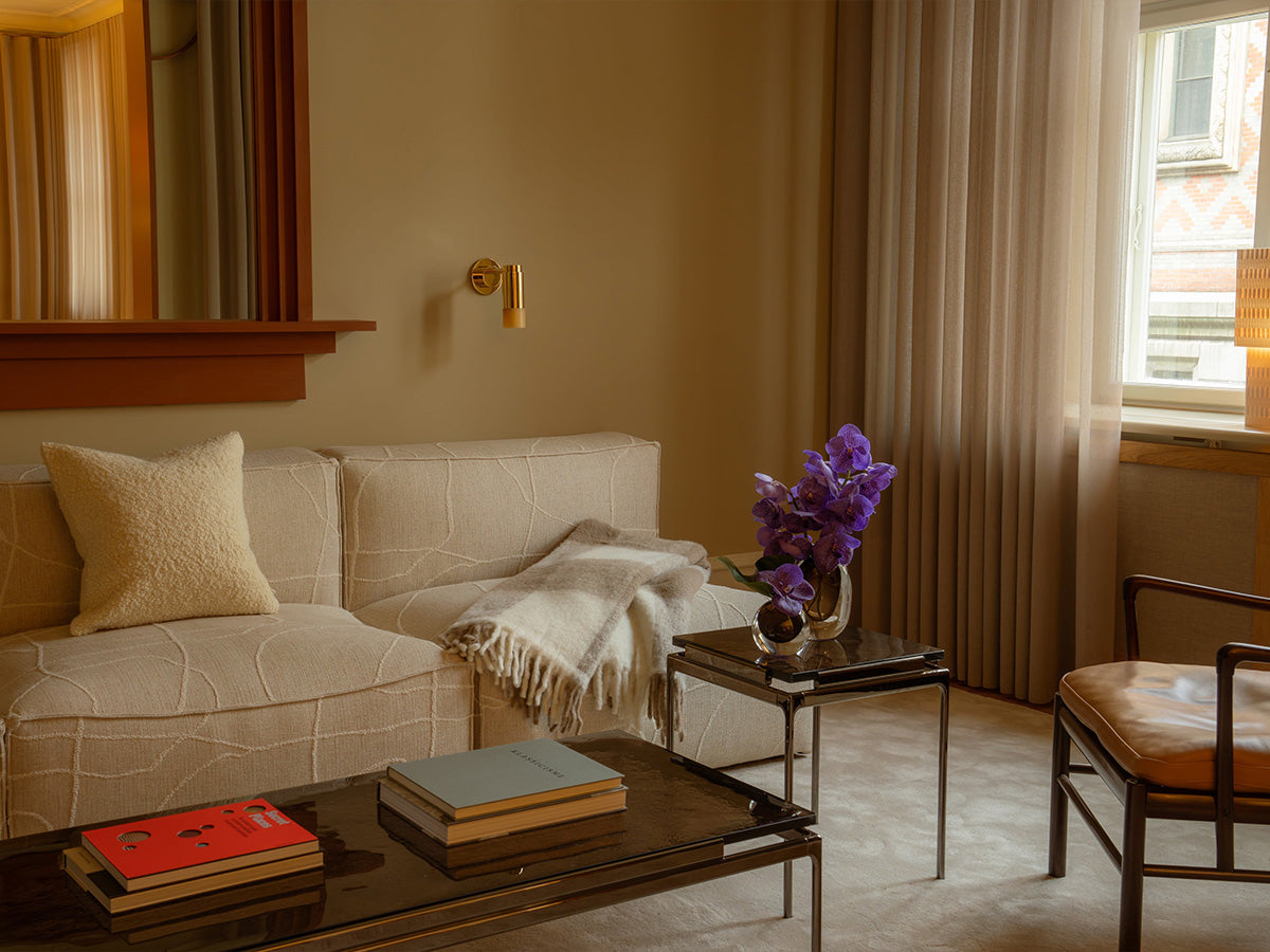 Elegant living room with beige sofa, plush rug, purple flowers, and modern decor by Massimo Copenhagen.